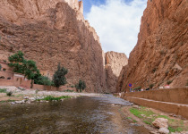 Eroded red rock cliffs tower over Todgha River in Todra Gorges, Morocco.