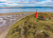 Lighthouse at the Wadden island Texel in the dunes during a calm autumn afternoon with reflections on the North Sea beach. The Eierland lighthouse is located at the North point of the island.